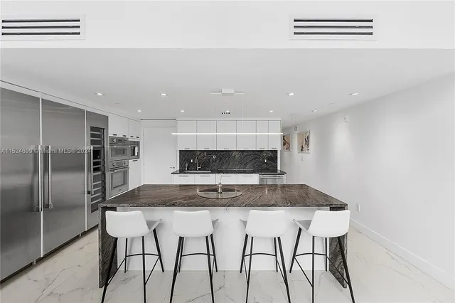 a kitchen with kitchen island a counter top space cabinets and stainless steel appliances