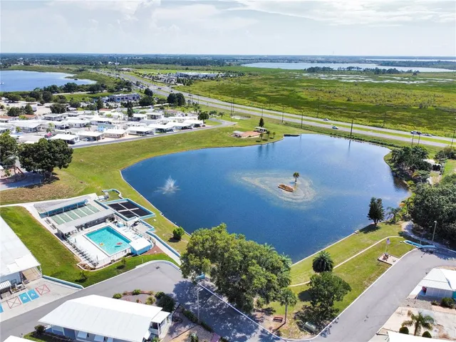a view of swimming pool with lawn chairs and large trees