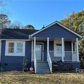 a view of a house with a small yard plants and large tree