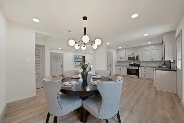 a view of a dining room and livingroom with furniture wooden floor a chandelier