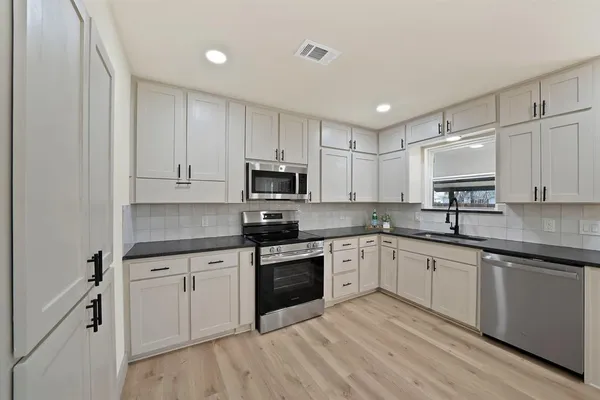 a kitchen with granite countertop white cabinets and white appliances