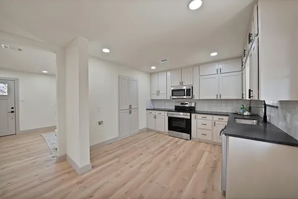 a kitchen with granite countertop a stove top oven and cabinets