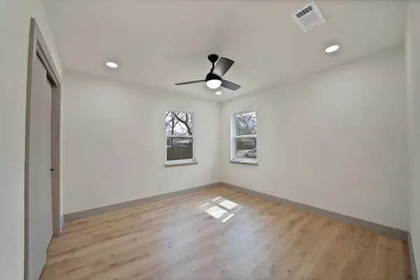 an empty room with wooden floor and windows
