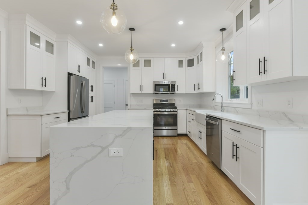 30 Oscars Way Dedham, MA 02026 - Photo 7 of 39 a large kitchen with stainless steel appliances kitchen island granite countertop a large stove a sink a refrigerator and white cabinets with wooden floor