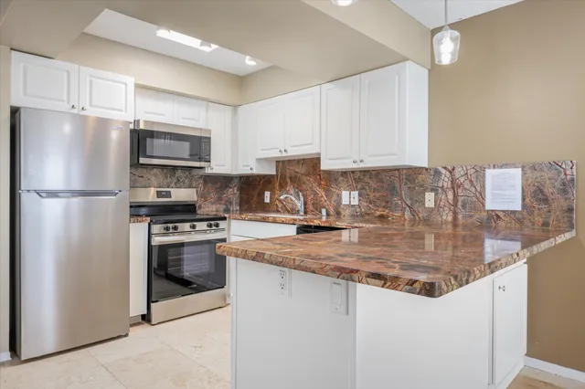 a kitchen with stainless steel appliances granite countertop a refrigerator a stove a sink and a microwave