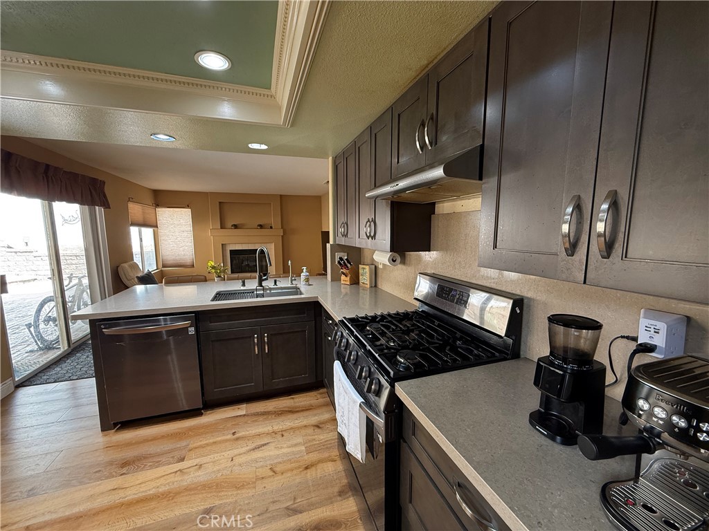 21182 Tennyson Road Moreno Valley, CA 92557 - Photo 14 of 36 a kitchen with stainless steel appliances granite countertop a stove a sink dishwasher and a refrigerator with wooden floor