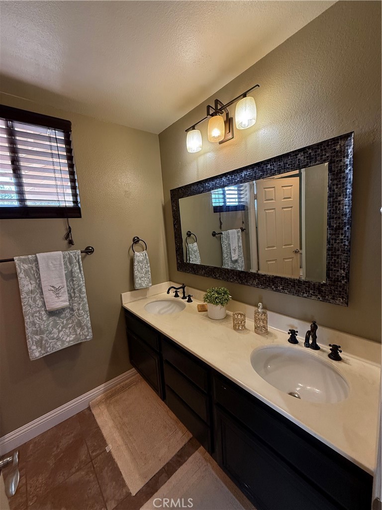 21182 Tennyson Road Moreno Valley, CA 92557 - Photo 25 of 36 a bathroom with a double vanity sink and a mirror