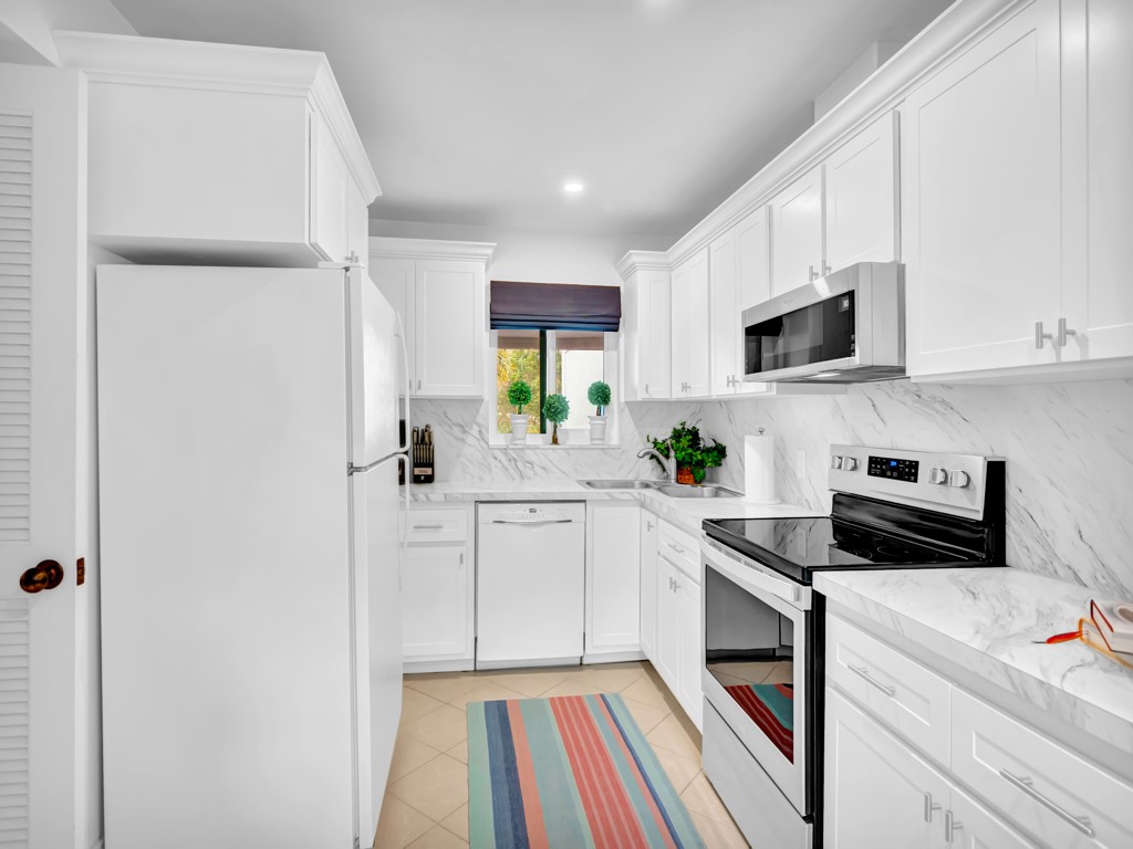 1155 Reef Road, Unit B2 Vero Beach, FL 32963 - Photo 7 of 32 a kitchen with white cabinets and appliances