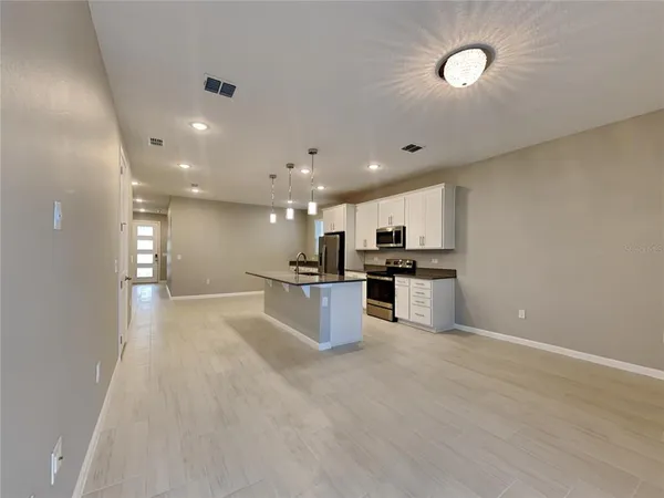 a view of kitchen with kitchen island stainless steel appliances sink cabinets and stove with wooden floor