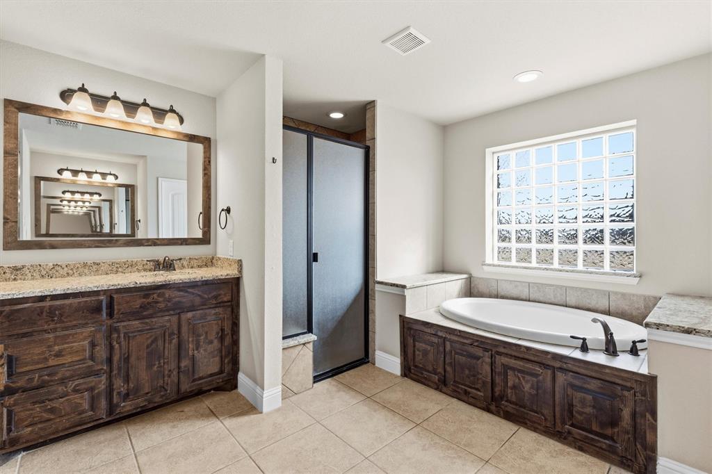 505 Water Fall Lane Nevada, TX 75173 - Photo 16 of 36 a spacious bathroom with a double vanity sink large mirror and a bathtub