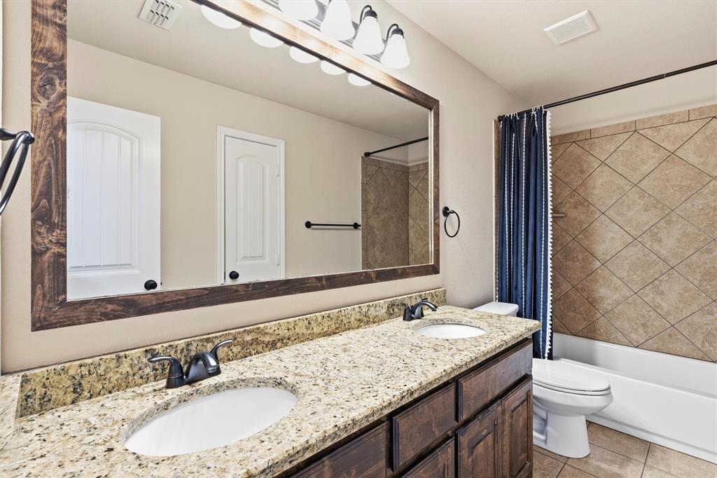 505 Water Fall Lane Nevada, TX 75173 - Photo 24 of 36 a bathroom with a granite countertop sink a toilet a mirror and shower