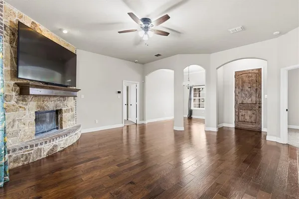 a view of a livingroom with a fireplace a ceiling fan and wooden floor