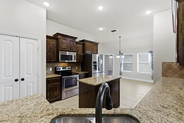 a kitchen with stainless steel appliances granite countertop a refrigerator a stove and a sink
