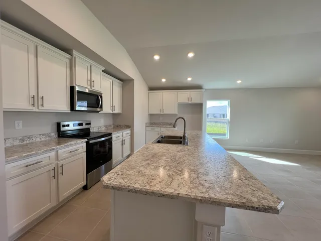 a large kitchen with stainless steel appliances a large counter top a stove and a refrigerator