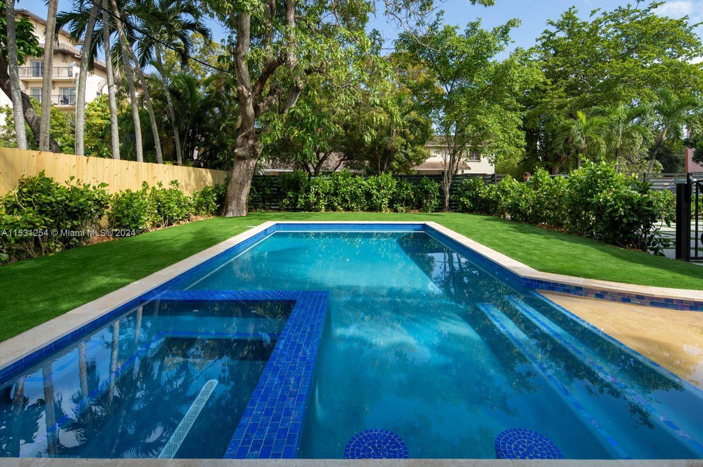 a view of backyard with swimming pool and green space