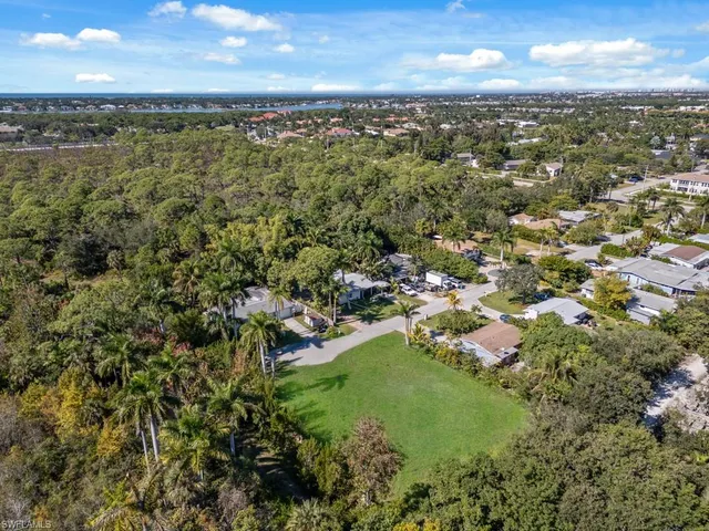 an aerial view of residential houses with outdoor space and trees