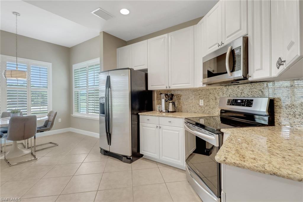 9208 Quartz Lane, Unit 102 Naples, FL 34120 - Photo 9 of 31 a kitchen with stainless steel appliances granite countertop a stove a sink and a microwave