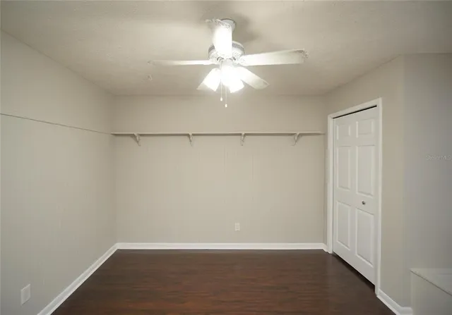 an empty room with wooden floor closet and windows