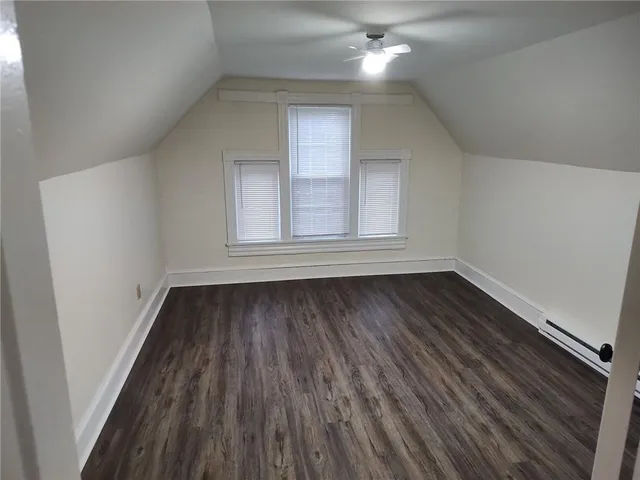 a view of an empty room with wooden floor and fan
