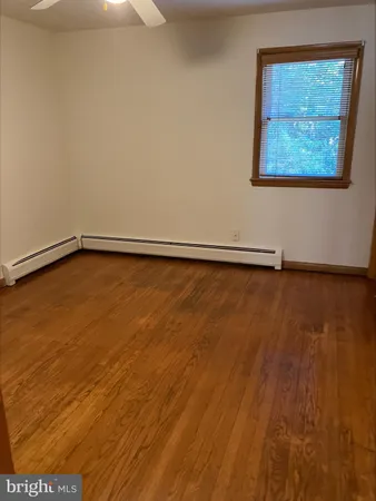 a view of an empty room with wooden floor and a painting on the wall