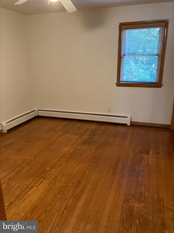 a view of an empty room with wooden floor and a painting on the wall