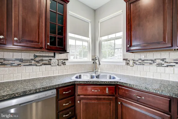 a kitchen with granite countertop stainless steel appliances a sink window and cabinets