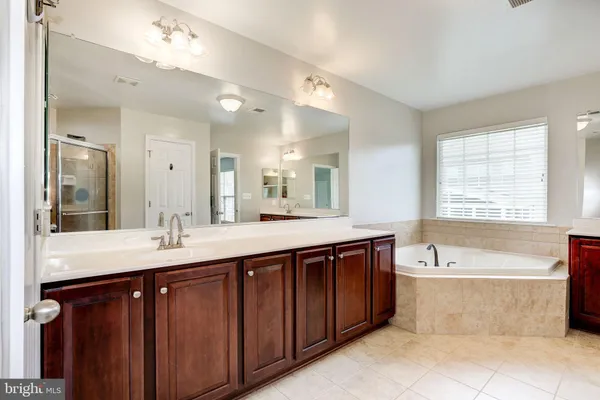 a spacious bathroom with a sink double vanity granite tub shower and a mirror