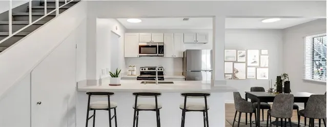 a kitchen with stainless steel appliances a sink table and chairs