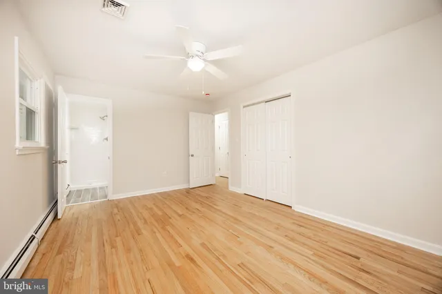 an empty room with wooden floor and fan