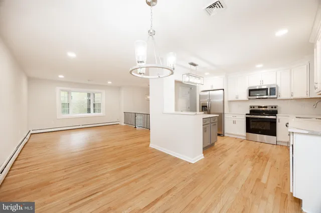 a kitchen with stainless steel appliances a refrigerator and wooden floor