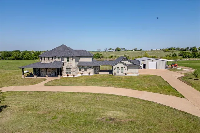 a view of a big house with big yard and large tree