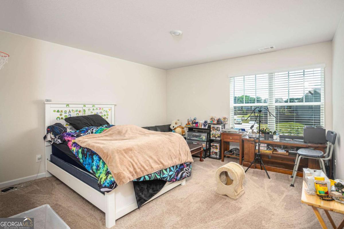 653 Meadows Farm Way Monroe, GA 30655 - Photo 25 of 34 a bedroom with a bed table and chairs