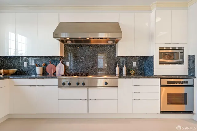 a kitchen with granite countertop a refrigerator and white cabinets