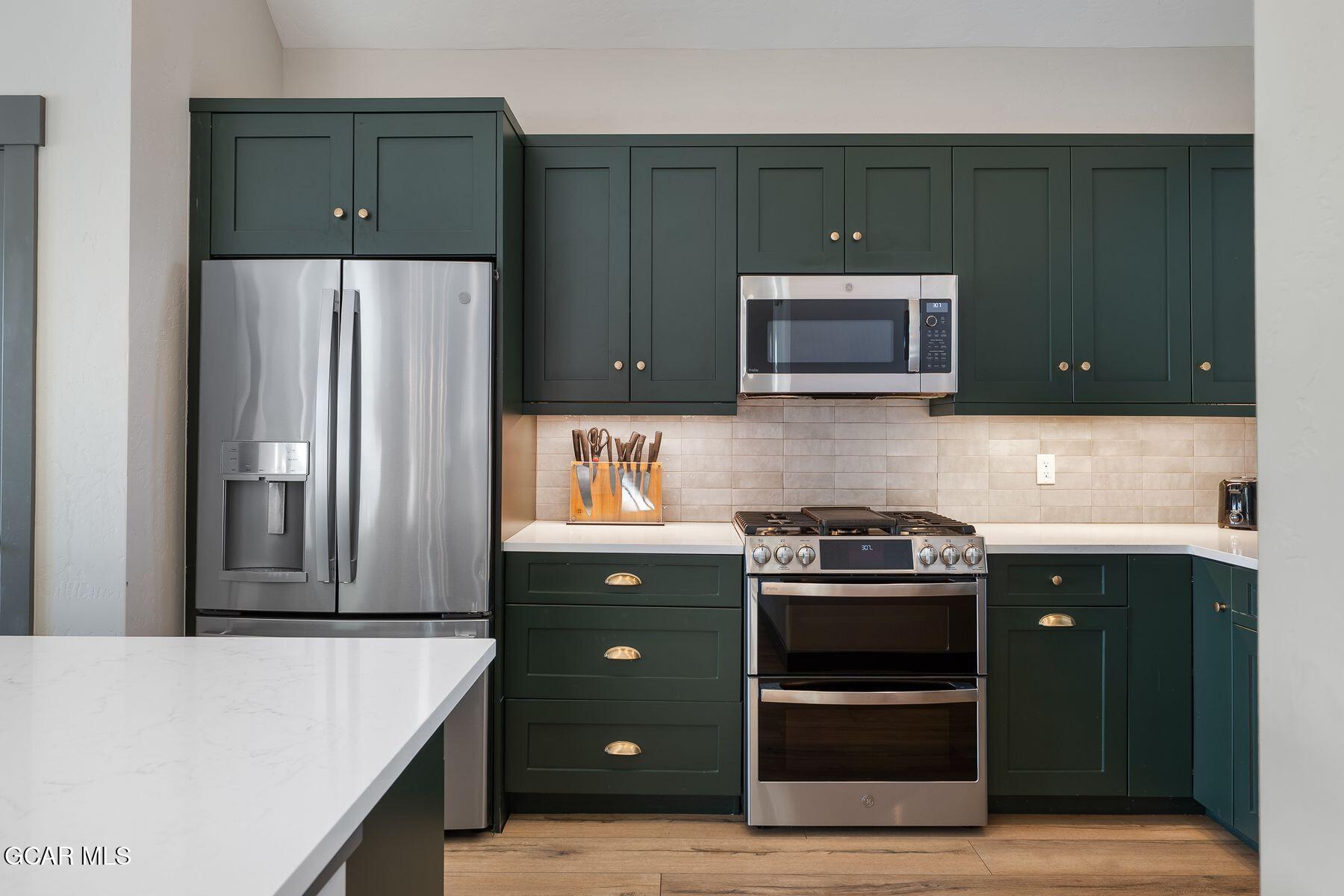 a kitchen with stainless steel appliances granite countertop a refrigerator stove and microwave