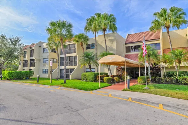 a front view of a multi story residential apartment building with yard and green space
