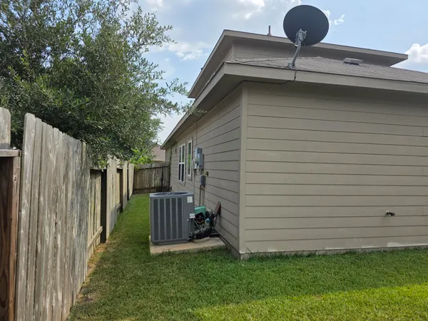 a view of a backyard with large trees and wooden fence