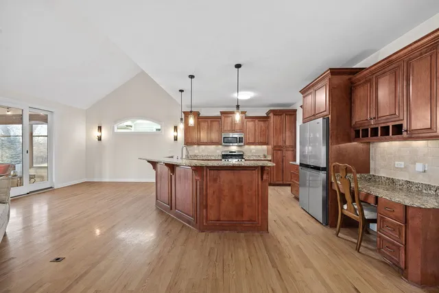 a kitchen with stainless steel appliances granite countertop a stove a sink dishwasher a refrigerator white cabinets and wooden floor