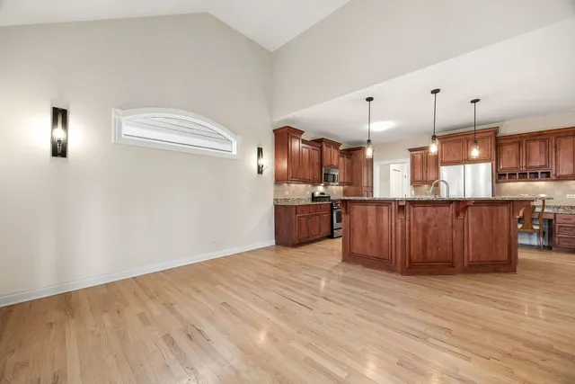 a kitchen with stainless steel appliances kitchen island wooden floors and white walls