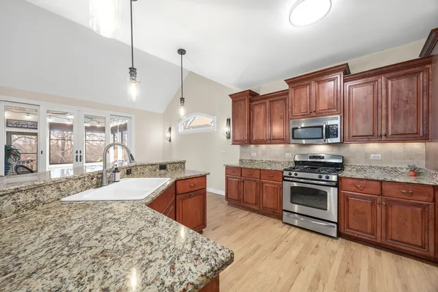 a large kitchen with granite countertop a stove top oven a sink a counter space and cabinets