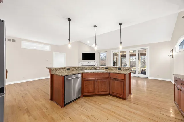 a kitchen with stainless steel appliances granite countertop a sink a stove and a wooden floor