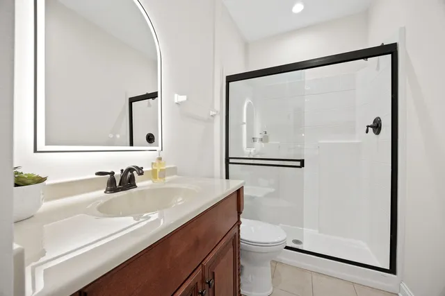 a bathroom with a sink a toilet a mirror and shower