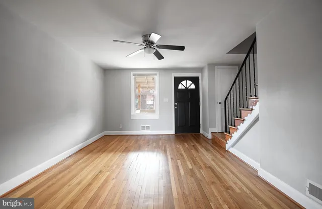 a view of an empty room with wooden floor and a window