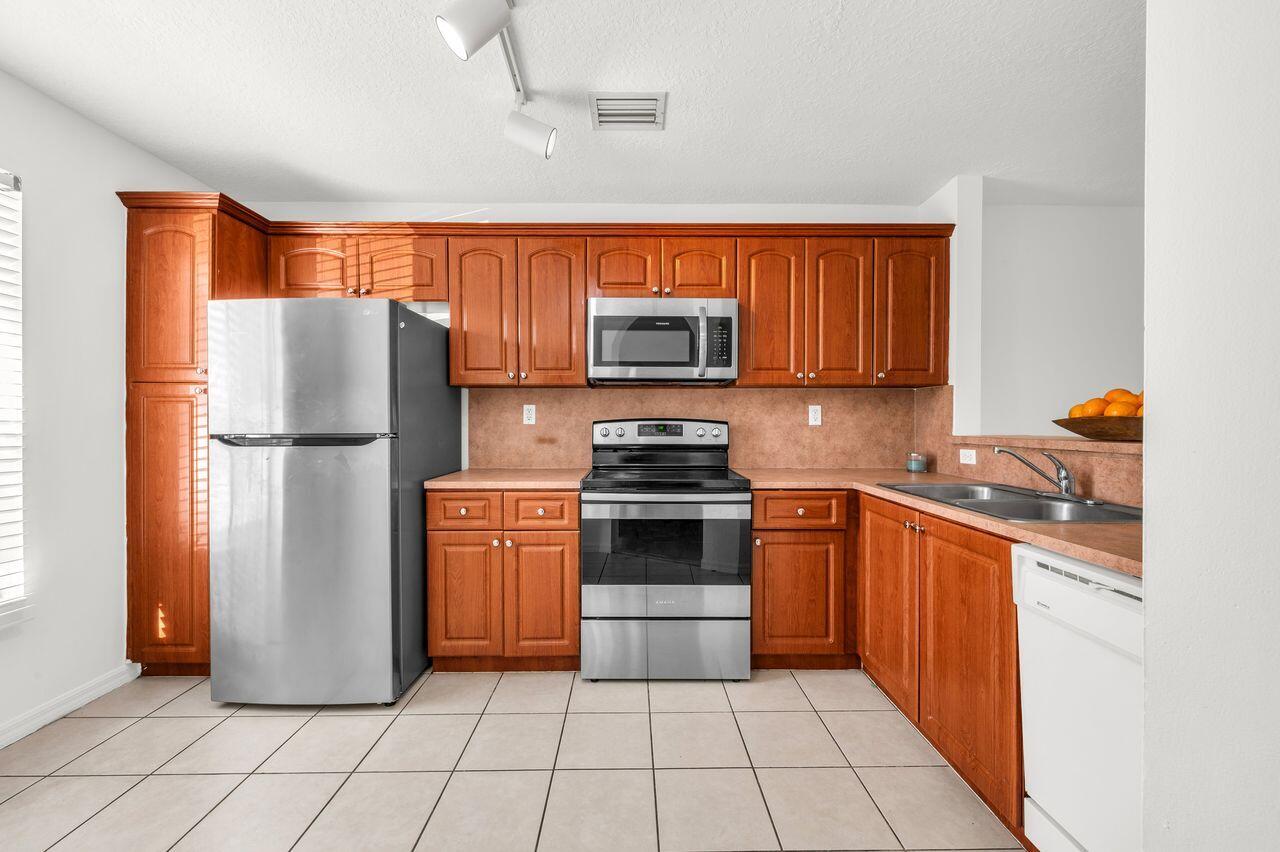 3169 Southwest 129th Terrace, Unit 164 Miramar, FL 33027 - Photo 4 of 20 a kitchen with granite countertop a refrigerator and a stove top oven
