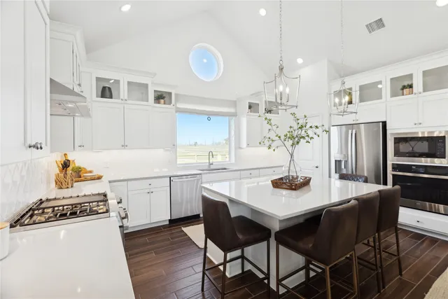 a kitchen with stainless steel appliances kitchen island granite countertop a dining table and chairs