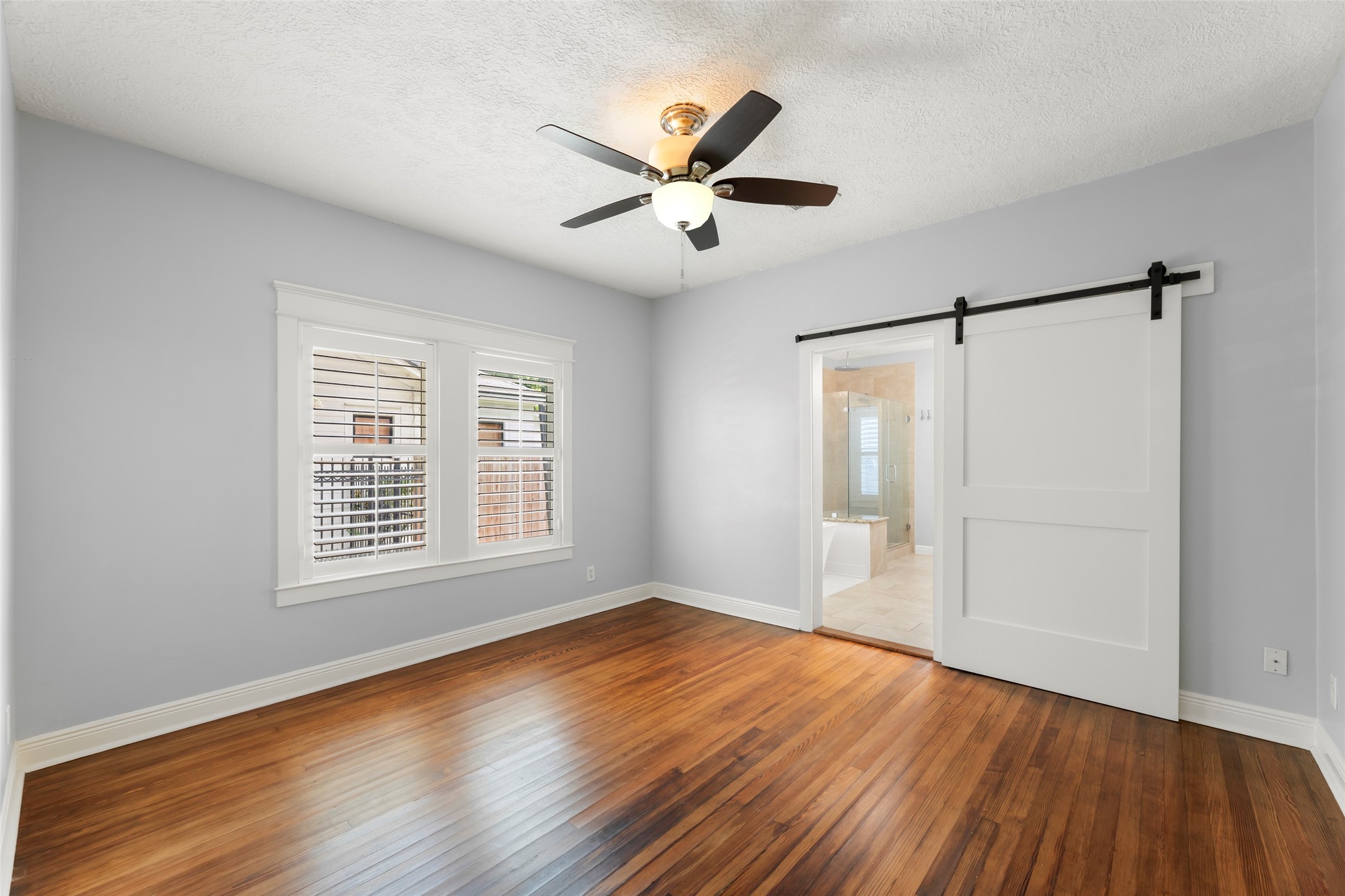 1120 Winston Street Houston, TX 77009 - Photo 18 of 35 The primary suite is a light-filled sanctuary, featuring sun-drenched windows and a stylish barn door that adds a touch of rustic character to the space.