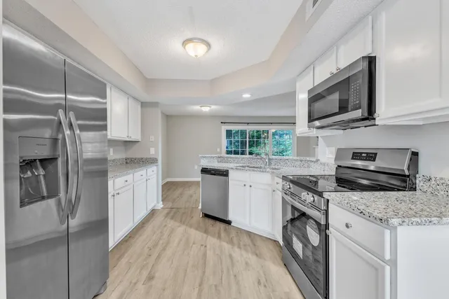 a kitchen with stainless steel appliances kitchen island granite countertop a refrigerator and cabinets