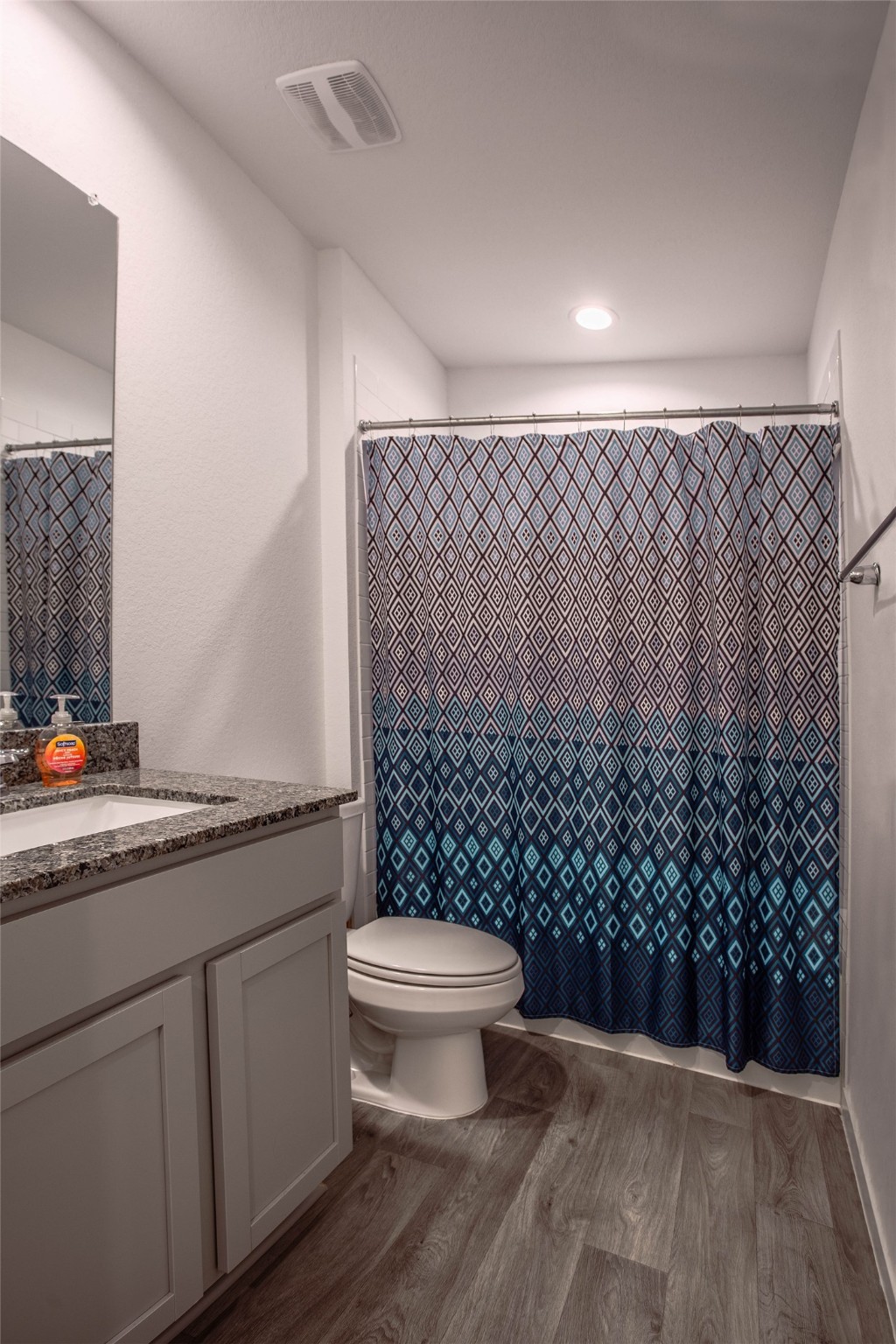 31810 Whittis Hill Way Fulshear, TX 77441 - Photo 14 of 23 This spacious full secondary bathroom features a granite countertop vanity, under-sink storage, and a combination tub and shower with modern tile. The space is finished with sleek recessed lighting for a clean, polished look. There is extra shelving off to the left.