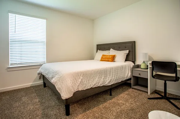 a bedroom with a bed chair and a window