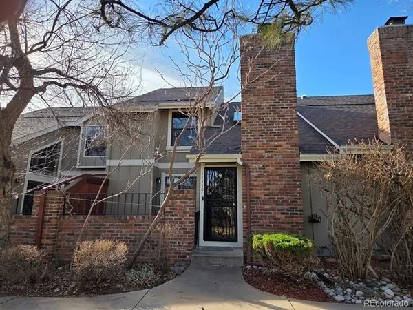 a brick building with a small yard and potted plants