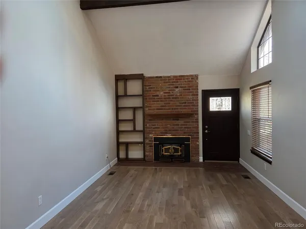 a view of empty room with fireplace and wooden floor